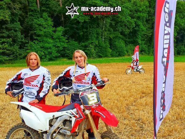 Motocross für Frauen: zwei Fahrerinnen in Honda-Trikots halten ihren Helm neben einer Honda in der Hand