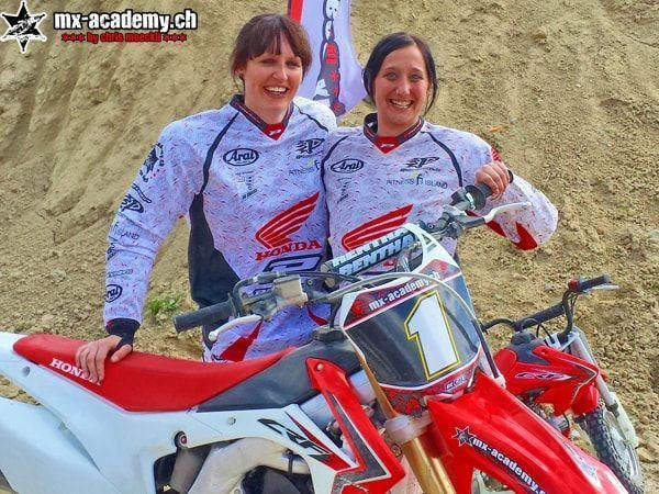 Zwei lächelnde Fahrerinnen in Honda-Trikots stehen neben einer Honda mit der Startnummer 1