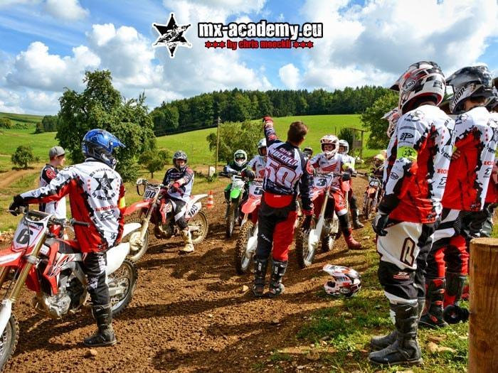 Jugend Motocross: Jugendliche stehen mit ihren Motorrädern bei der Instruktion durch den Trainer