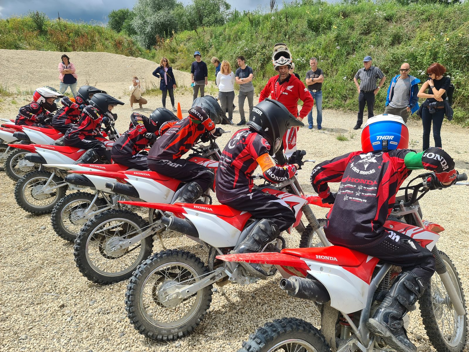 Kinder Motocross im Gruppenkurs: Kinder und Eltern stehen mit ihren Honda-CRF-Motorrädern zusammen