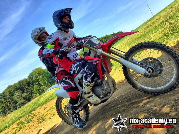 Motocross Training: Fahrer hebt das Vorderrad seines Motorrads vom Boden ab und fährt auf dem Hinterrad